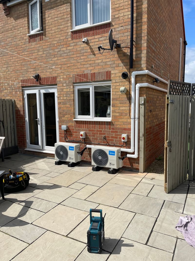 Two air conditioning outdoor units on a rear patio with tidy white trunking running up the wall