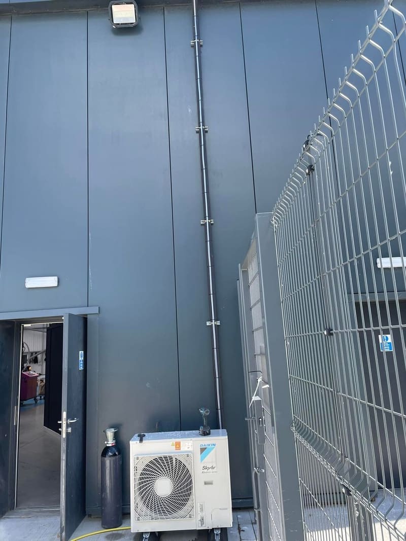 Air conditioning outdoor unit beside the entrance of a clad commercial building