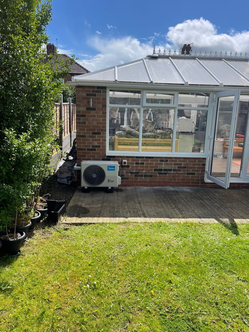 Conservatory with an air conditioning outdoor unit beside the patio doors