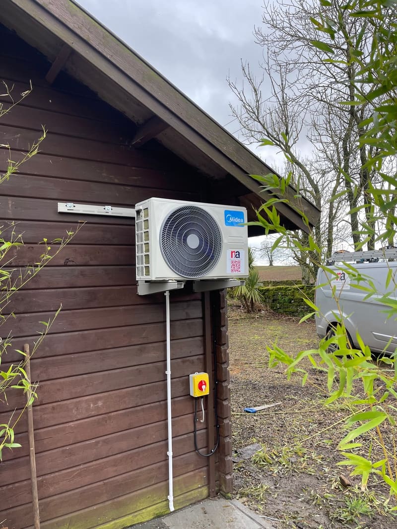 Air conditioning outdoor unit on the side of a timber garden room