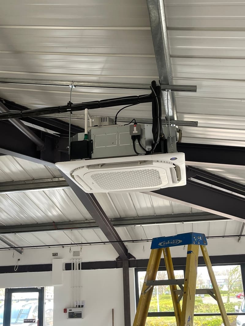 Ceiling cassette air conditioner suspended beneath the steel roof of a commercial unit