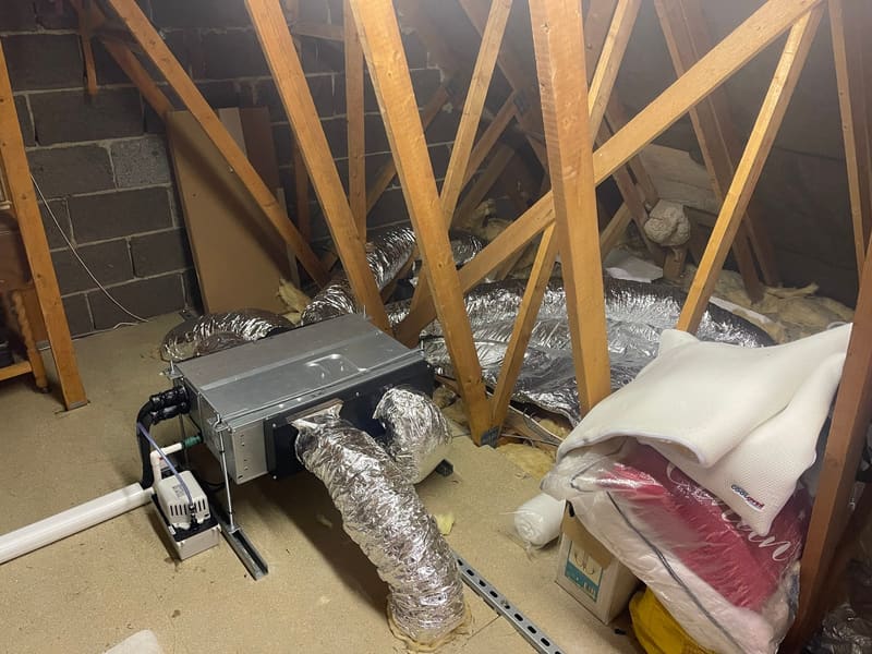 Ducted air conditioning unit installed between the rafters of a loft