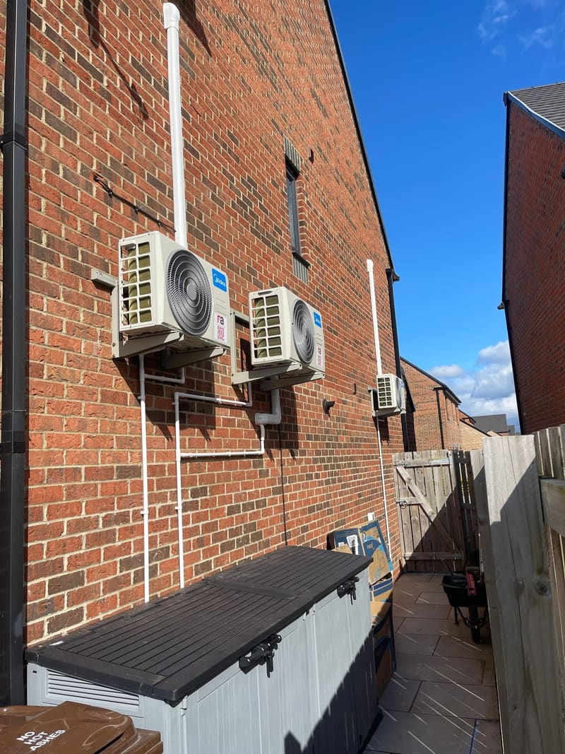 Two air conditioning outdoor units mounted on wall brackets on a brick house in Medway